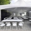White high-peak marquee tent set up on a paved driveway with rows of white folding chairs and rectangular tables for an outdoor event in Vancouver, BC.