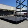 16x20 black portable stage with stairs and black skirting set up in the courtyard at Trev Deeley Motorcycles in Vancouver, BC